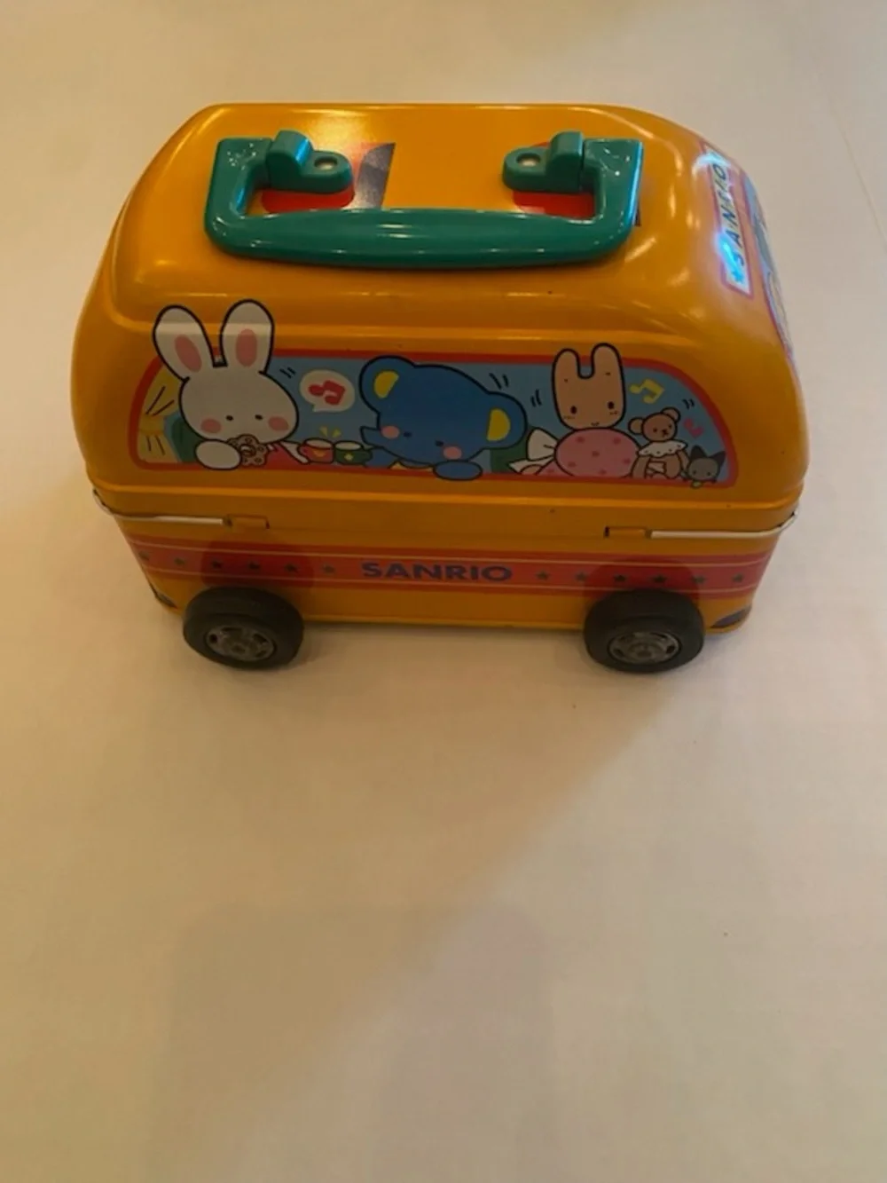 A Sanrio Yellow Toy Bus Metal Carry Case with Teal Handle